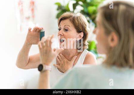 Elderly woman using asthma inhaler in clinic Stock Photo