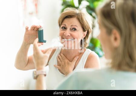 Elderly woman using asthma inhaler in clinic Stock Photo