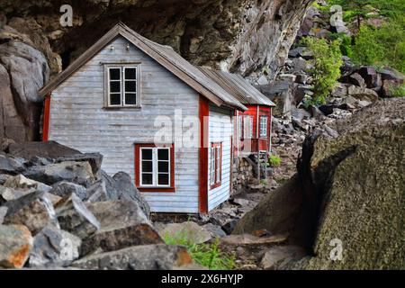 Norway landmark. Helleren old homes hidden beneath huge rock cliff overhang in Jossingfjord. Stock Photo