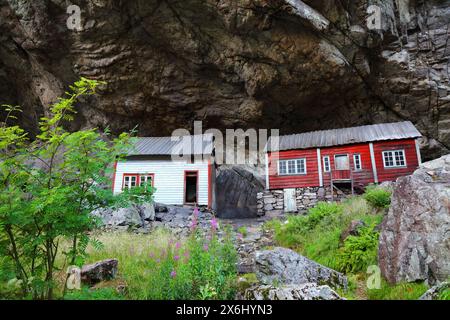 Norway landmark. Helleren old homes hidden beneath huge rock cliff overhang in Jossingfjord. Stock Photo