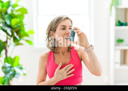woman using asthma inhaler in white clinic Stock Photo