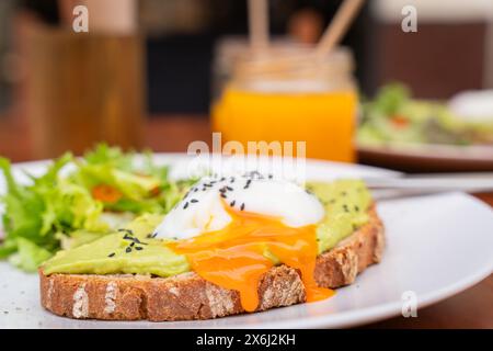 Toast with avocado cream and poached egg on top. Delicious breakfast. Whole Wheat Toast with Avocado Cream topped with a Poached Egg.selective focus. Stock Photo