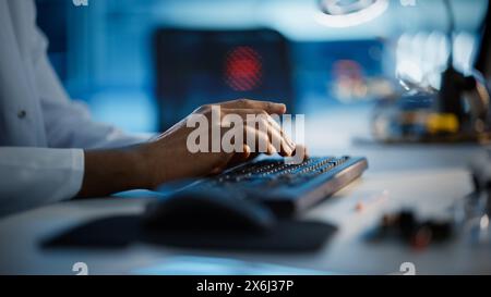 Modern Electronics Research, Development Facility: Engineer Working on Computer, Typing with His Hands on a Keyboard. Scientist Design PCB, Silicon Microchips, Semiconductors. Close-up Focus on Hands Stock Photo