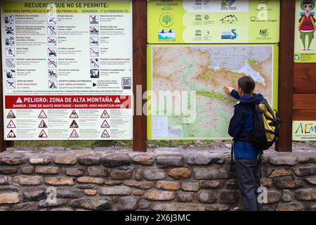 PYRENEES, SPAIN - SEPTEMBER 25, 2021: Tourist points to hiking trail map in Ordesa y Monte Perdido National Park in Pyrenees. Stock Photo