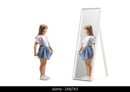 Little girl holding her skirt and looking into a mirror isolated on white background Stock Photo