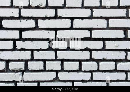 Close-up of a white-painted brick wall, showing detailed texture and imperfections in the paint and bricks, ideal for backgrounds or textural contrasts Stock Photo