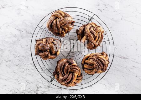 Freshly baked caramel-cinnamon knots on a cake rack Stock Photo