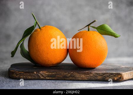 Oranges with leaves on wooden board Stock Photo