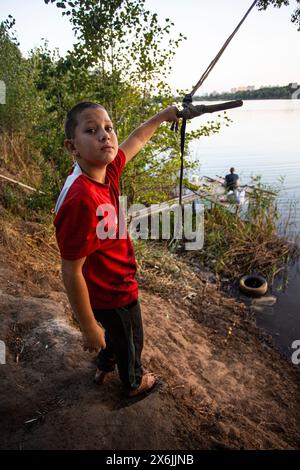 Young boy is preparing to jump a primitive self-made wooden bungee (Tarzanka)  on the shore in Ukraine, a popular water jumping attraction. Stock Photo