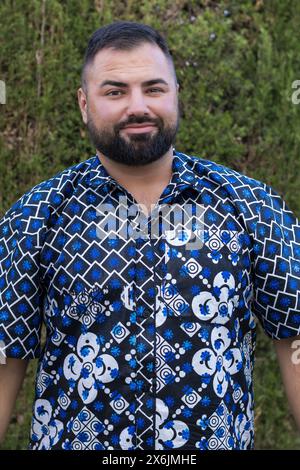 This portrait captures the essence of contentment in a 30-year-old man, his vibrant patterned shirt reflecting the cheerful spirit he embodies. Stock Photo