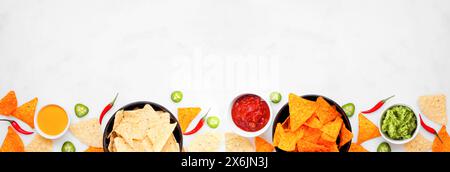 Nachos and dip bottom border. Top view on a white marble banner background. Copy space. Stock Photo