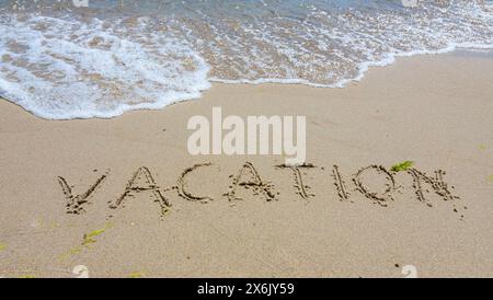 Handwritting inscription Vacation word on tropical sandy beach, travel concept card for holidays. Stock Photo