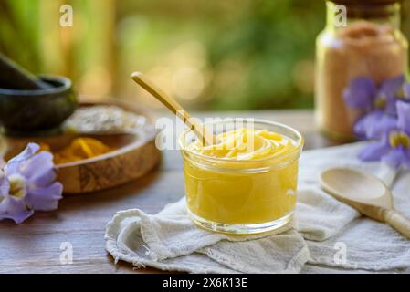 Ghee butter in glass jar with wooden spoon on wooden table with blurred background. Stock Photo