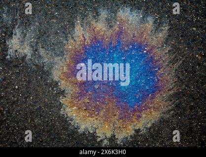 Oil stain with rainbow colours on a wet asphalt road Stock Photo