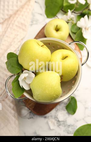 Colander with fresh apples and beautiful spring blossom on white marble ...