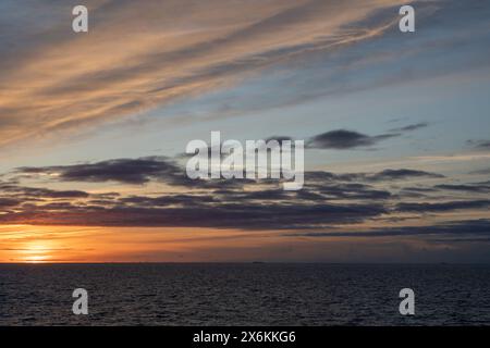 sunset, with a cloudy sky, over the ocean Stock Photo