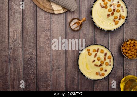 Resting on a rustic brown wood background are two bowls of creamy white asparagus soup, beckoning with warmth and comfort Stock Photo