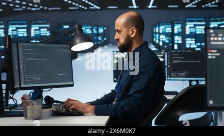 IT specialist in server farm ensuring valuable data remains shielded from potential threats, safeguarding against unauthorized access and vulnerabilities, securing system from virus attacks Stock Photo