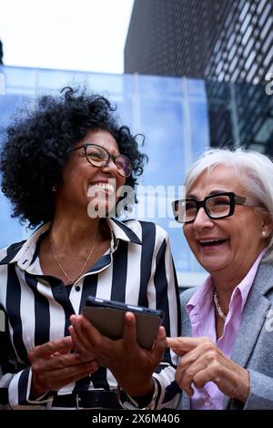 Professional business women talking about work matters using and looking tablet pc in their hands Stock Photo