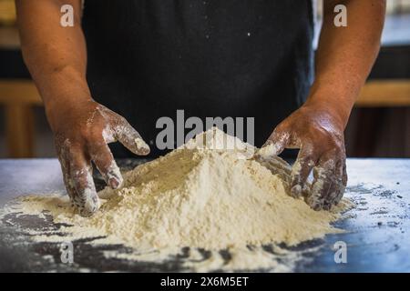 Baker's hands ready to knead a mound of flour, isolated on black background. prepares bread in the traditional way Stock Photo