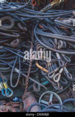 A close-up view of a tangled pile of industrial ropes and chains. The ropes are thick and frayed, and the chains are various sizes and link types. Stock Photo