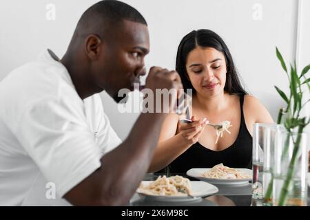 young latin interracial couple, sitting in the dining room eating spaghetti. man serious and angry with his wife. Stock Photo
