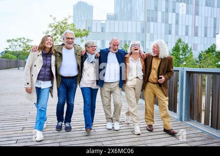 Group of smiling mature people walking carefree with their luggage enjoy vacations on street Stock Photo