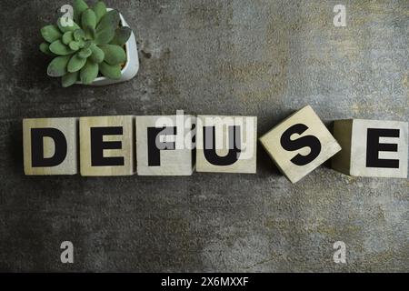 Concept of The wooden Cubes with the word Defuse on wooden background. Stock Photo