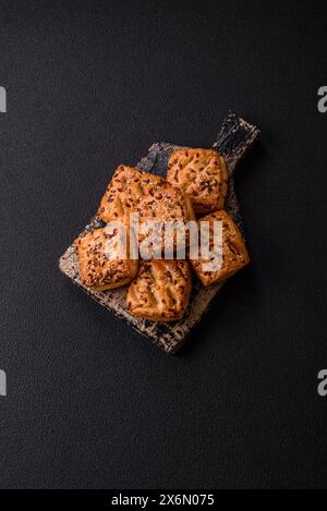 Triangular puffs with feta cheese, tomatoes with salt, spices and herbs on a dark concrete background Stock Photo