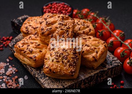 Triangular puffs with feta cheese, tomatoes with salt, spices and herbs on a dark concrete background Stock Photo