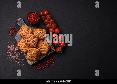 Triangular puffs with feta cheese, tomatoes with salt, spices and herbs on a dark concrete background Stock Photo