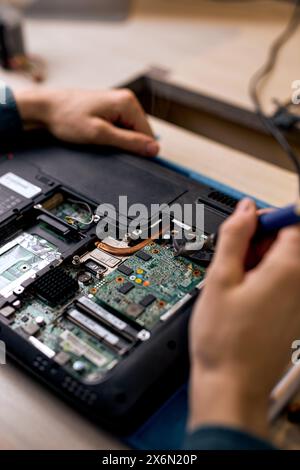 Hand technician repairing broken laptop notebook computer with tools, alone, at workshop. Unrecognizable professional specialist repairing computer. C Stock Photo