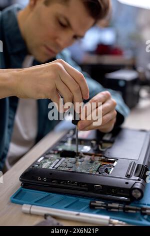 technician hold the screwdriver for repairing the laptop. computer hardware, repairing, upgrade and technology. professional technicial at workplace concentrated. focus on hands Stock Photo