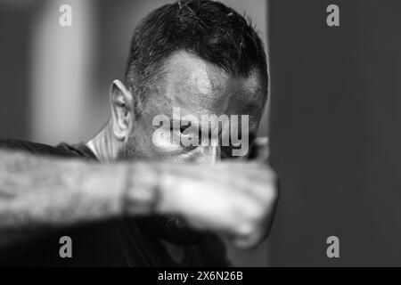 Portrait of muscular boxer. Boxer man punching boxing bag, close up. Fists fight. Mans fight, punches. Kicks up. In the outdoor boxing arena. Man read Stock Photo