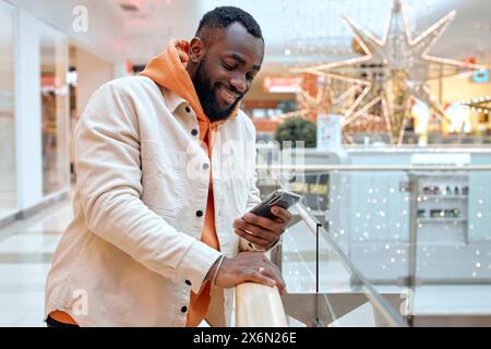 cheerful guy chatting with his girlfriend at business office. handsome joyful man enjoys sending message, texting sms, looking at the screen of cell p Stock Photo