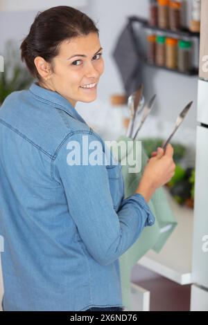 portrait of a young woman in the kitchen drying dishes Stock Photo