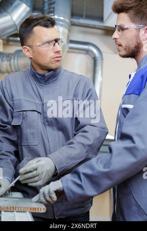 factory workers in gloves and goggles talking Stock Photo