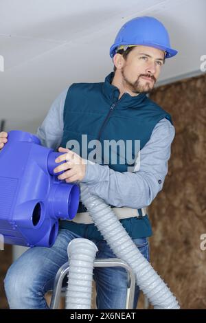 young male technician repairing air conditioner indoors Stock Photo