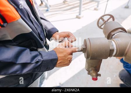 engineer man wearing a safety vest is working on a pipe valve to turn on off water pipe Stock Photo
