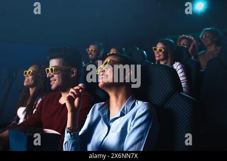 Group of cheerful people laughing while watching movie in cinema with 3D glasses. Stock Photo