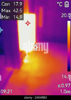 Leak detection using thermal imaging camera. Infrared image of a radiator and a heat plume in the floor from a leak in a hot water pipe. Central heati Stock Photo