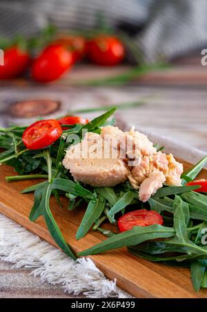 Light appetizer with rocket, tuna and red cherry tomatoes on a wooden cutting board Stock Photo