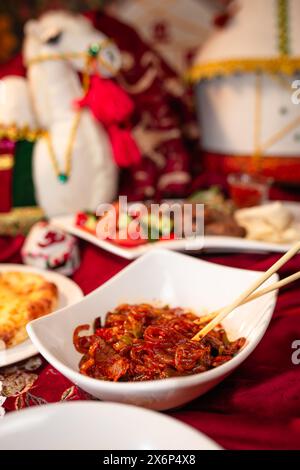 Delicious spicy noodles with meat and vegetables on a red tablecloth in a cafe Stock Photo