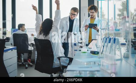Medical Science Laboratory: Black Scientist with use of Microscope, Discovers New Medicine and Celebrates it with Colleagues. Brilliant Young Specialists, Doing Innovative Research Stock Photo