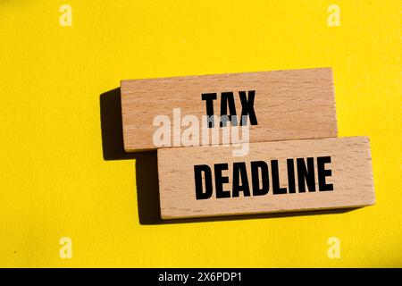 Tax deadline words written on wooden blocks with yellow background. Conceptual tax deadline symbol. Copy space. Stock Photo