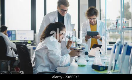 Medical Science Laboratory: Beautiful Black Scientist Discovers New Drug Compound and Celebrate it with Her Colleagues. Happy Young Specialists, Doing Innovative Experiments in Advanced Laboratory. Stock Photo