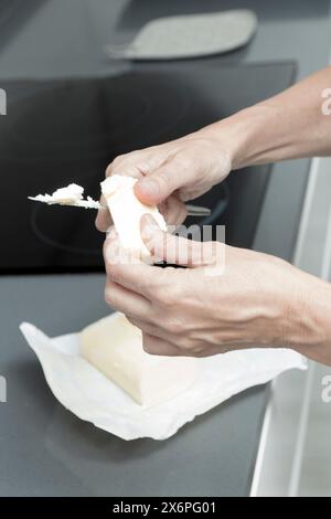 buttering bread near a stovetop, with butter block and knife, in a modern kitchen focus on action Stock Photo