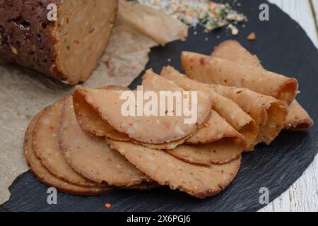 Seitan shaped and cooked in ham press, sliced on slate board. Vegan protein, plant based alternative to meat. Stock Photo