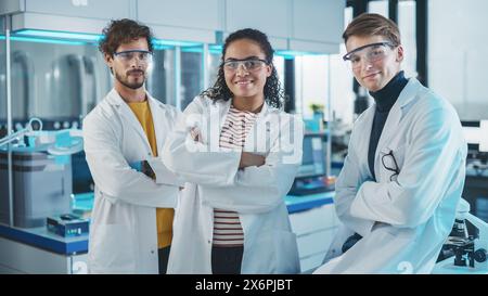 Medical Science Laboratory with Team of Three Young Successful Scientists. Beautiful Black Female, Handsome Latin and Caucasian Male Scientists Smile while Looking at Camera. Medium Portrait Shot Stock Photo