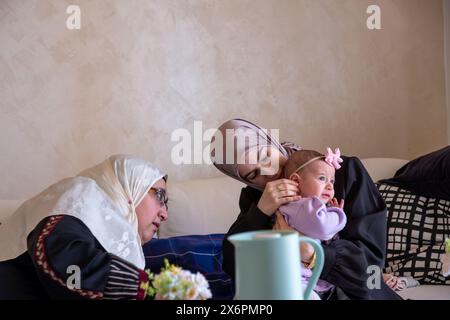 Mother and grandmother are playing with baby wearing beautiful clothes celebrating and enjoying their moments with children Stock Photo